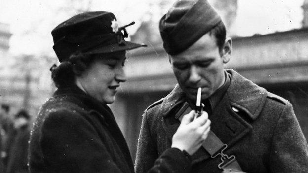 Woman lights cigarette for GI