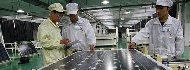 Workers inspecting solar panels at a factory in China