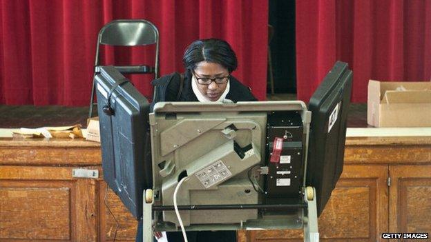 woman stands at electric voting machine