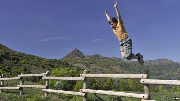Girl jumping over fence near border between France and Spain