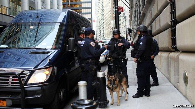 Police men and a police dog stand next to a police van