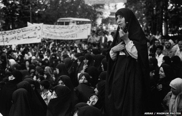 A militia woman armed with an Uzi sub-machine gun controls a demonstration against Iraq, Tehran, 1979