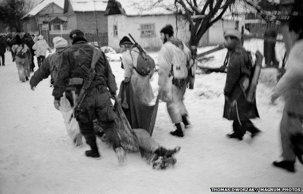 Chechen fighters drag a fallen comrade in Alkhan-Kala, 2000