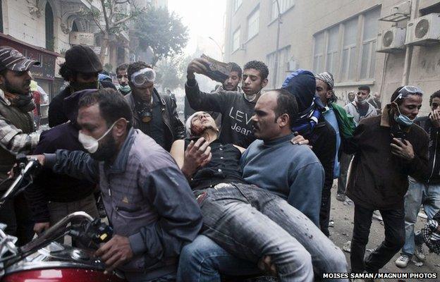 A protester with a wound to the head is evacuated on a motorcycle from clashes in Tahrir Square in Cairo, 22 November 2011