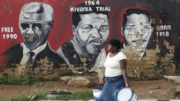 A woman walks past a mural depicting portraits of former South African President Nelson Mandela in Soweto, South Africa, Tuesday 11 December 2012