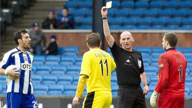 Paul Cairney is booked by Bobby Madden