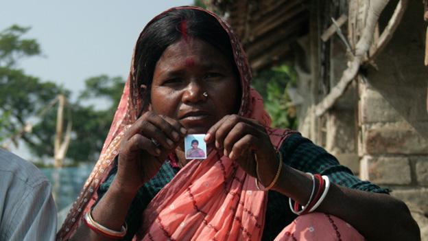 A woman holds up a picture of her daughter who has been missing for two years