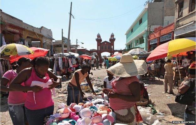 A woman at a stall with the Iron Market in the distance