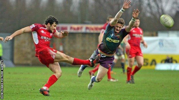 Hallam Amos of Dragons charges down a kick by Ryan Davis of London Welsh