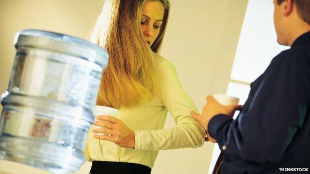 Man grabbing a woman's arm at the watercooler