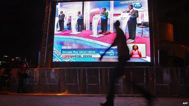 A man walks past a large screen in Central Nairobi broadcasting the last televised debate for the 2013 Kenya elections on 25 February 2013