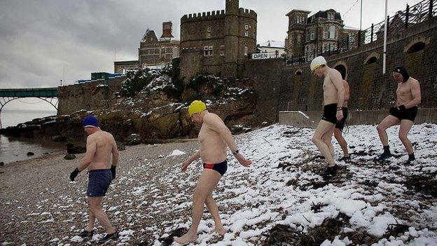 Clevedon sea swimmers walk down a snow covered beach.