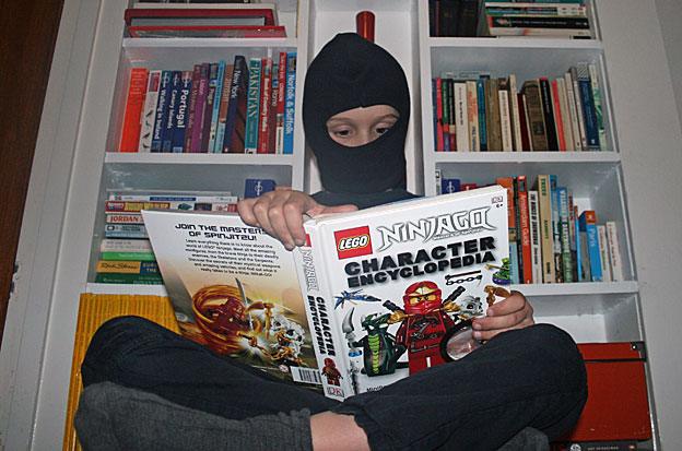 Casciani Junior reading Ninjago Character Encyclopaedia while dressed as a ninja