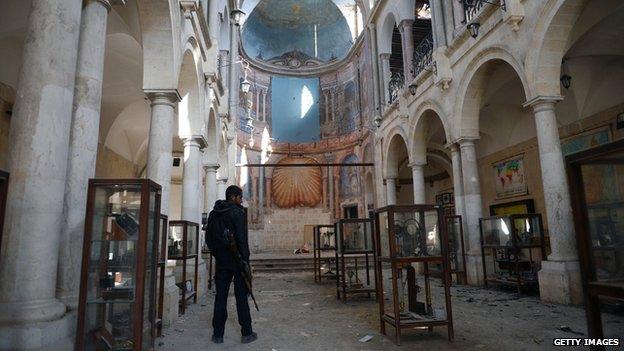 A Syrian rebel looks at damaged display cases inside a former church turned into a film museum which was shelled by government forces in Aleppo's old city on January 17, 2013.