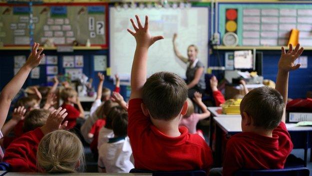 Children putting their hands up in class