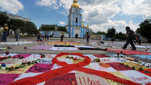 People walk past quilts laying on Mikhaylovskaya Square in Kiev made by HIV positive people to commemorate AIDS victims in Ukraine