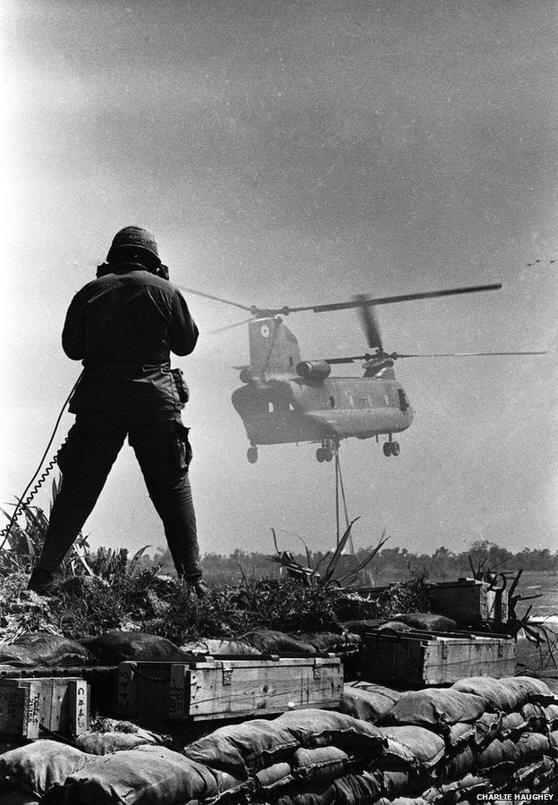 An RTO (radio telephone operator) guides a Chinook delivering a sling load of materials and supplies at Fire Support Base Pershing, near Dau Tieng