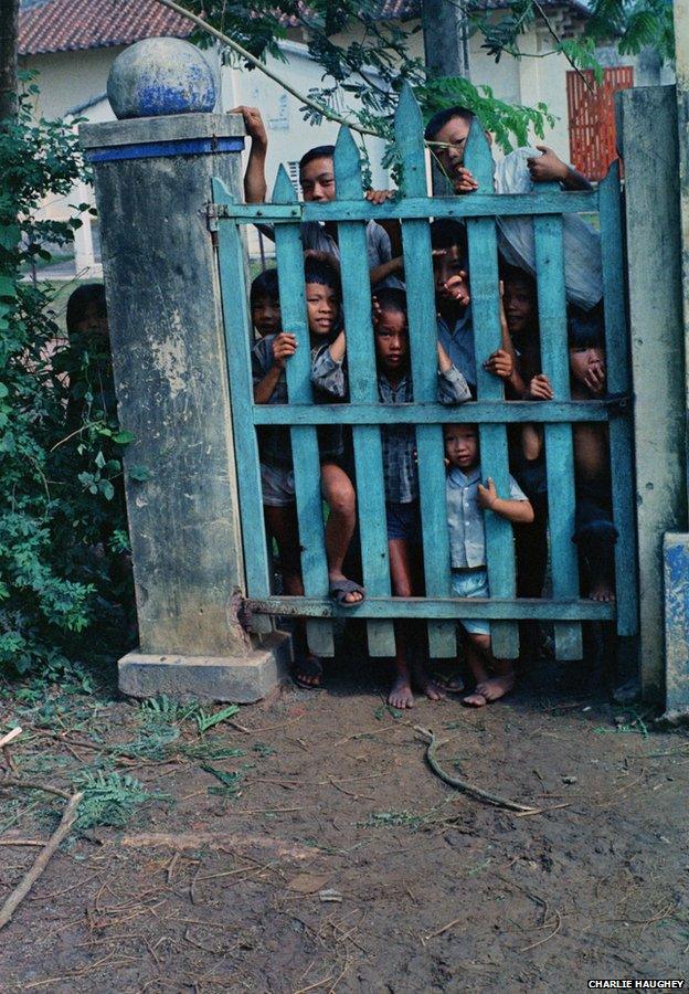 Vietnamese children peer through a gate at Haughey's camera