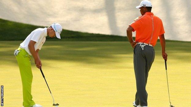 Tiger Woods watches as Guan Tianlang putts