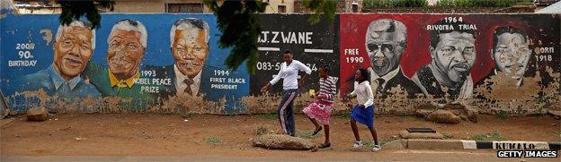 People walk past a mural of Nelson Mandela's timeline in Johannesburg