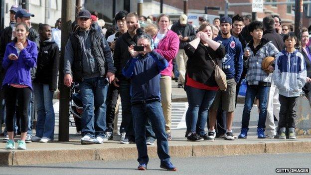 Crowd at the Boston Marathon; a man takes a picture with his phone