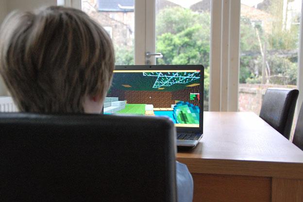 Boy plays Minecraft at kitchen table