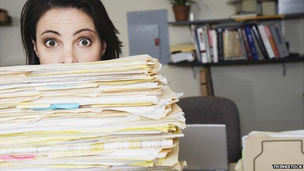 Woman looking over the top of files