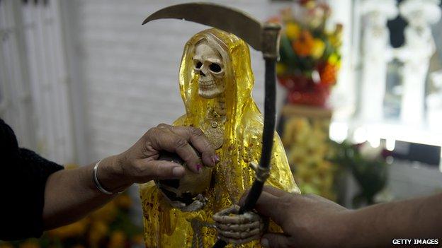 Devotees touch the figure of Santa Muerte at an altar in Mexico City on 1 November, 2012