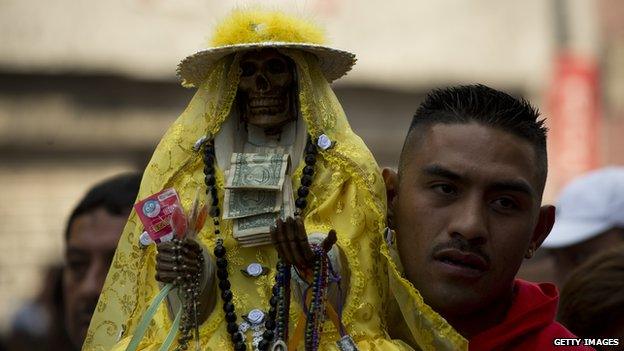 A man carries a statue of Santa Muerte during a procession in Mexico Cit on 1 November 2012