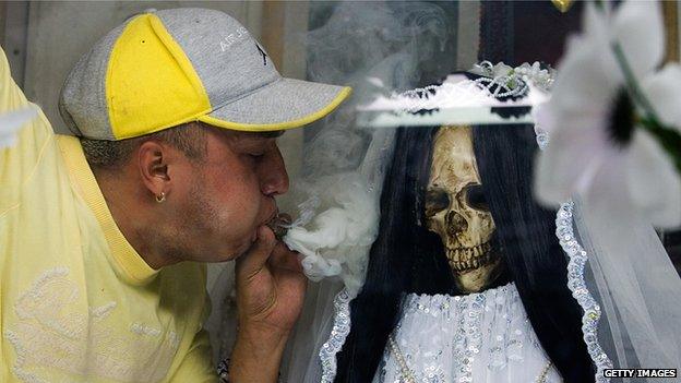 A devotee blows smoke at a statue of Santa Muerte on 1 November 2007