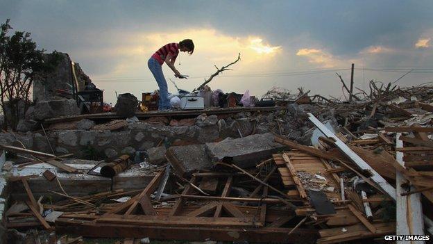 Woman stands on top of her demolished home in Joplin, Missouri