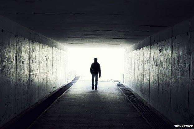 Man in tunnel walking towards light