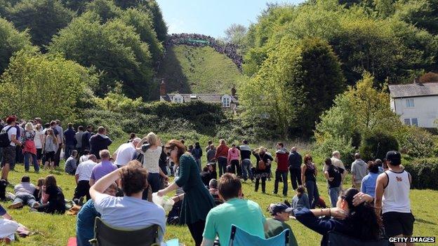 People sit and watch the cheese-rolling races