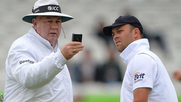 Umpire Steve Davis checks the light meter, watched by England's Jonathan Trott