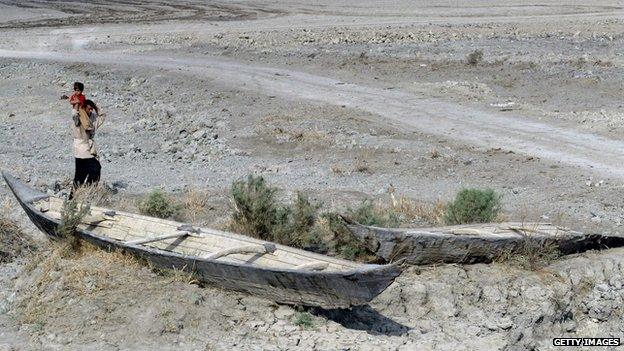 A man and child stand in arid former wetland