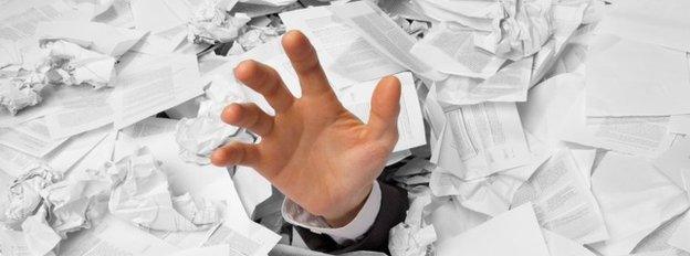 Hand reaching out from pile of paper