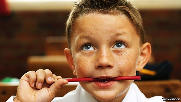 A boy thinking with a pencil in his mouth