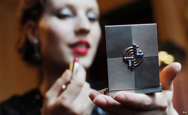 Woman applying lipstick in the mirror of a Gatsby-style make-up box