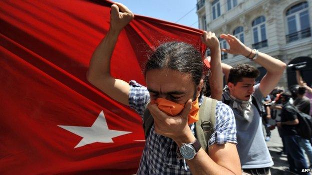 Protesters hold a large Turkish flag in front of a water cannon truck, Istanbul, 31 May 2013