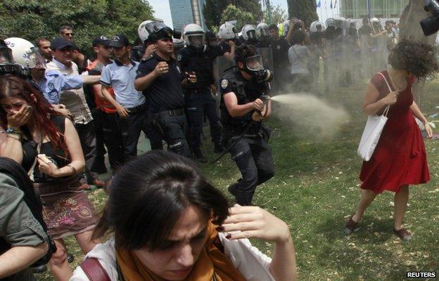 A Turkish riot policeman uses tear gas against Ceyda Sungur in Taksim Square