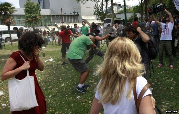 A Turkish riot policeman uses tear gas against Ceyda Sungur in Taksim Square