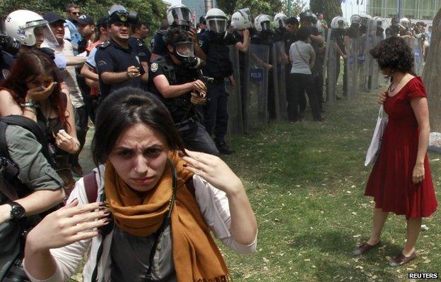 A Turkish riot policeman uses tear gas against Ceyda Sungur in Taksim Square