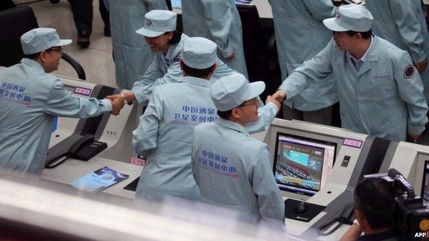 Chinese technicians congratulate each other after the Shenzhou-10 rocket launched successfully from the Jiuquan space centre