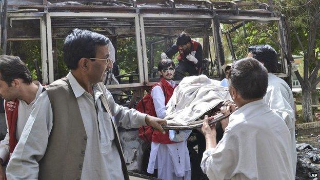 Pakistani police and volunteers gather at the wreckage of a bus destroyed in a bomb blast in Quetta, Pakistan, 15 June