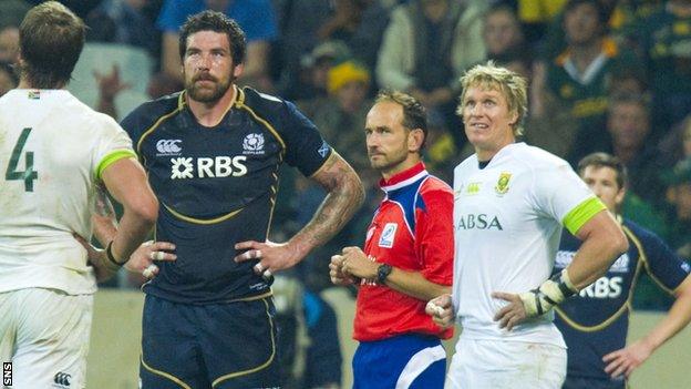 Referee Roman Poite (centre) awaits a replay of an incident involving Jim Hamilton (left) before showing the Scotland lock a yellow card