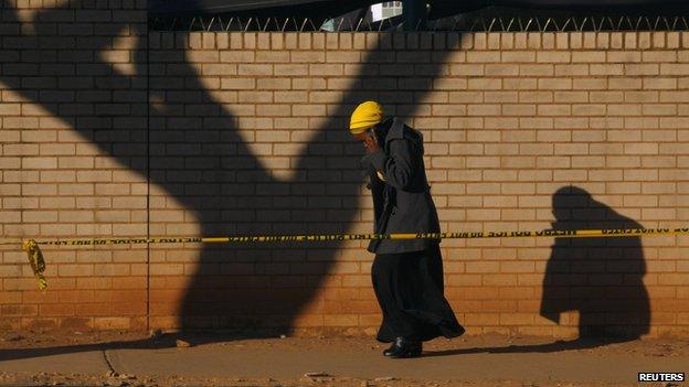 A woman talks on a mobile phone as she walks behind a police cordon outside a Pretoria hospital where former South African President Nelson Mandela is being treated