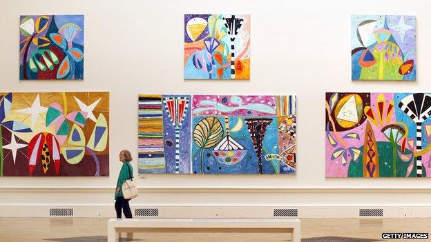 A visitor looks at paintings hanging at The Royal Academy Summer Exhibition