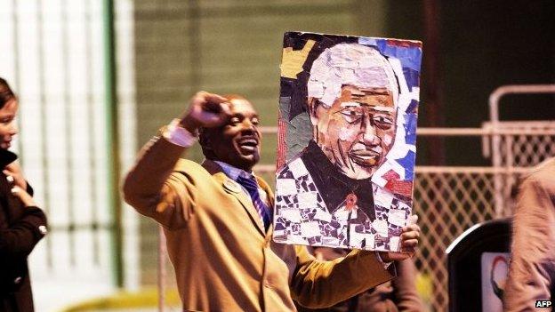 A man holds a picture of Mandela outside the hospital.