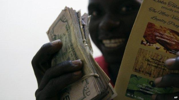 An tobacco farmer shows off his cash after selling his tobacco, at Boka Tobacco auction floors, in Harare, Zimbabwe, Tuesday 14 May 2013