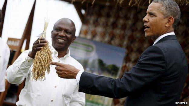 US President Barack Obama points to a rice crop before it is processed as he visits a food security expo in Dakar 28 June 2013